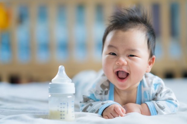 Asian Newborn baby smile with milk power bottle